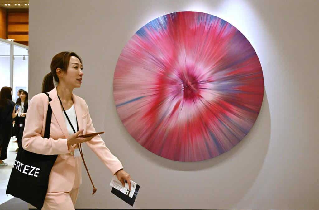 A woman walks past an artwork named "Beautiful Remastered Rubellite Tourmaline Painting, 2007" by artist Damien Hirst during the Frieze Seoul 2023 art fair in Seoul on September 6, 2023.